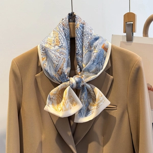 Elegante foulard in seta con stampa floreale blu e gialla annodato su un blazer marrone