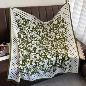 Flat lay of a green and white polka dot scarf with rose floral patterns on a leather sofa