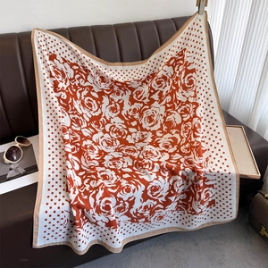 Detailed pattern of orange and beige polka dot silk scarf featuring camellia flower prints
