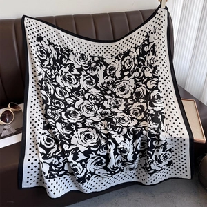 Detail of black and white rose pattern scarf with polka dots on a leather bench