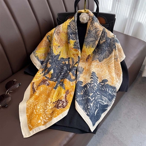 Floral jungle print square scarf draped elegantly over a luxury handbag and leather sofa