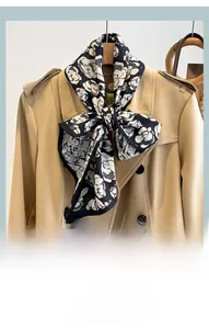 Detailed view of camel flower print neck scarf styled as a bow on a classic trench coat