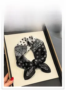 Macro detail of silk square scarf featuring black and white paisley and polka dot patterns
