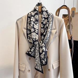 Elegant camellia floral silk scarf in black and white worn over a beige suit blazer