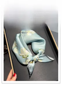 Detail of silk square scarf in mint green with elegant floral patterns on tray