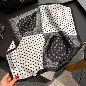 Close-up of silk scarf with polka dot and paisley pattern on a tray with accessories