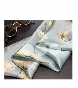 Macro detail of silk scarf showing light blue floral pattern and smooth texture