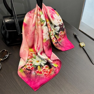 Foulard en soie élégant aux motifs floraux roses drapé sur un sac à main noir chic