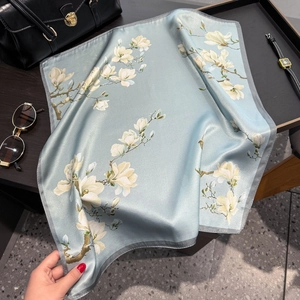 Elegant light blue silk scarf with white magnolia pattern on a premium black handbag