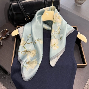 Elegant light green silk scarf with magnolia print paired with a stylish navy blue outfit