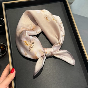 Elegant champagne silk scarf with magnolia flower print displayed on a tray