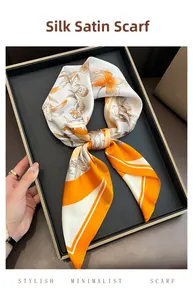 Vue détaillée d'un foulard carré en satin de soie à motif floral orange sur un plateau