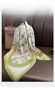 Détail d'un foulard en soie verte à fleurs élégamment drapé sur un sac à main en cuir chic