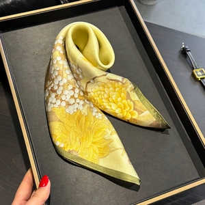 Fashionable bright yellow silk sunflower scarf with green rolled edges in a jewelry tray
