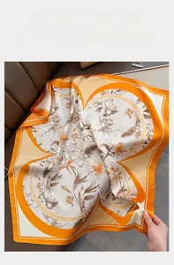 Détail d'un foulard en soie à imprimé lys avec bordures orange vif sur texture cuir