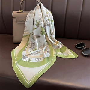 Écharpe élégante en imitation soie à motif floral et bordure verte sur un sac beige