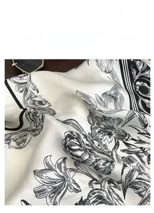 Detail of satin scarf showing ivory fabric with black floral patterns and silky drape
