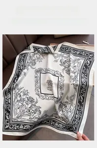 Close-up of elegant cream satin scarf featuring detailed black floral patterns and border