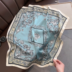 Detail of silk-like scarf with blue floral prints and baroque patterns on leather surface