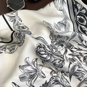 Detail of faux silk scarf with elegant vintage black floral print on cream fabric
