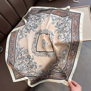 Detailed texture of champagne silk-like scarf with floral print and geometric border