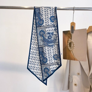 Detail of a long blue paisley silk scarf draped on a metal rack with a suit
