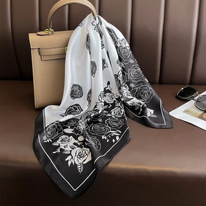 Elegant faux silk scarf with rose pattern draped on a khaki handbag for a stylish look