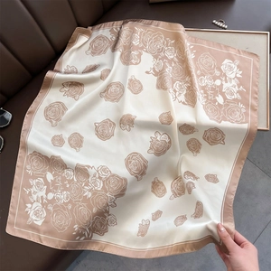 Close-up of rose print silk-like satin square scarf draped on a dark leather surface