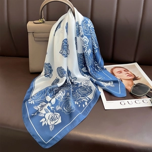 Blue and white floral faux silk scarf tied to a leather bag for an elegant fashion look