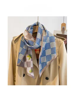 Détail d'un foulard doux avec motif floral bleu marine sur un trench-coat beige clair
