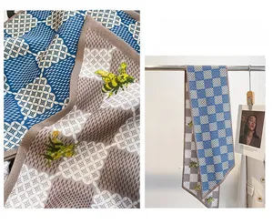 Détail d'une écharpe en soie étroite avec damier et broderie d'abeille élégante