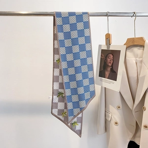 Écharpe longue en soie aux motifs géométriques bleus, stylisée sur un blazer