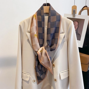 Élégant foulard en soie à motif géométrique bleu marine noué sur un blazer beige