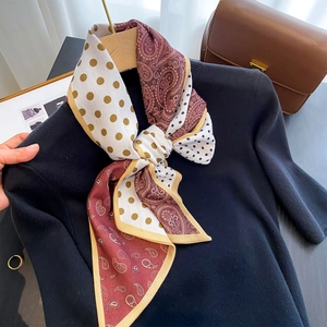 Elegant silk scarf with red paisley and gold polka dots draped over a black sweater