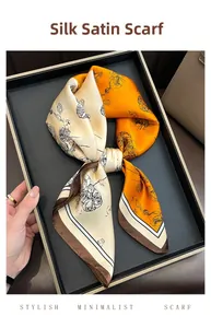 Detail of satin silk-like square scarf featuring orange floral print and geometric border