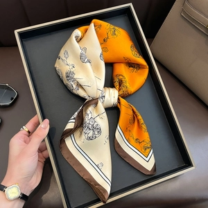 Elegant orange and beige floral silk scarf with striped borders on a display tray