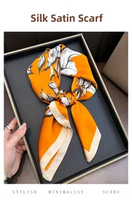 Detailed texture of orange silk-like square scarf with abstract floral patterns and beige hem