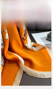 Close-up of vibrant orange silk scarf featuring precise edge stitching and satin texture