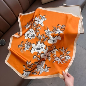 Elegant orange floral square silk scarf for women shown on a leather surface