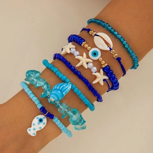 Detail of layered bohemian bracelets with blue beads, sea shells and starfish charms