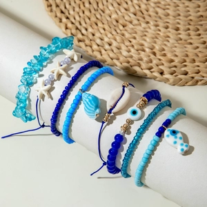 Detail of beach-style beaded bracelets set with sea shell and evil eye charms
