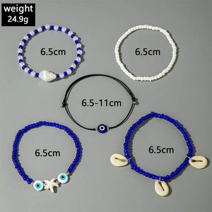 Detail of 5-piece bohemian beaded bracelet set with starfish, evil eye and shell charms