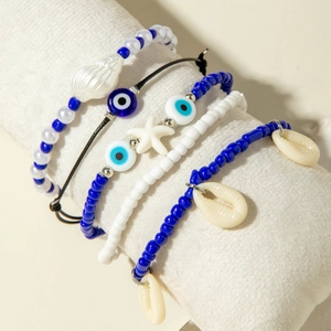 Detail of bohemian bracelets with blue beads, sea shells and starfish on a white cushion