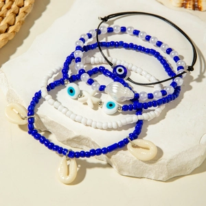 Detail of layered bohemian bracelets with pearl beads, sea shells and evil eye charms