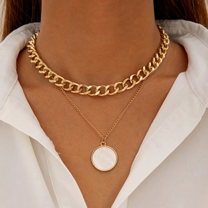 Detail of layered gold double necklace with white shell circular pendant on white shirt