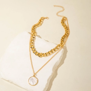 Detail of layered gold necklaces with flat curb chain and round white shell pendant