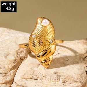 Macro shot of gold shell ring with pearl and zircon inlay on a natural stone surface