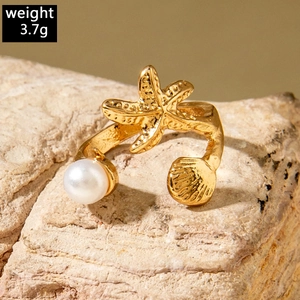 Macro shot of gold starfish ring with a round white pearl on a textured rock base