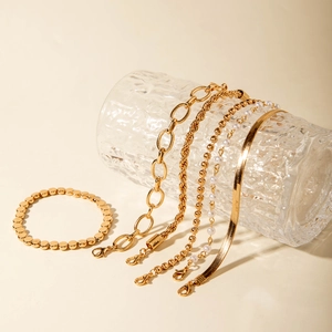 Détail d'un ensemble de 5 bracelets dorés avec perles d'imitation et design varié
