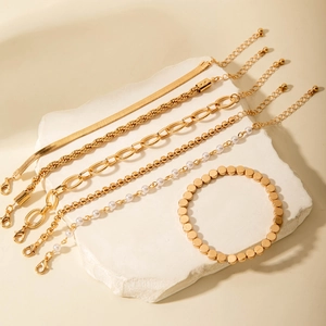 Vue détaillée d'un ensemble de 6 bracelets dorés avec perles sur présentoir en pierre